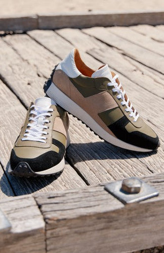 Pair of brown and black sneakers on a wooden surface